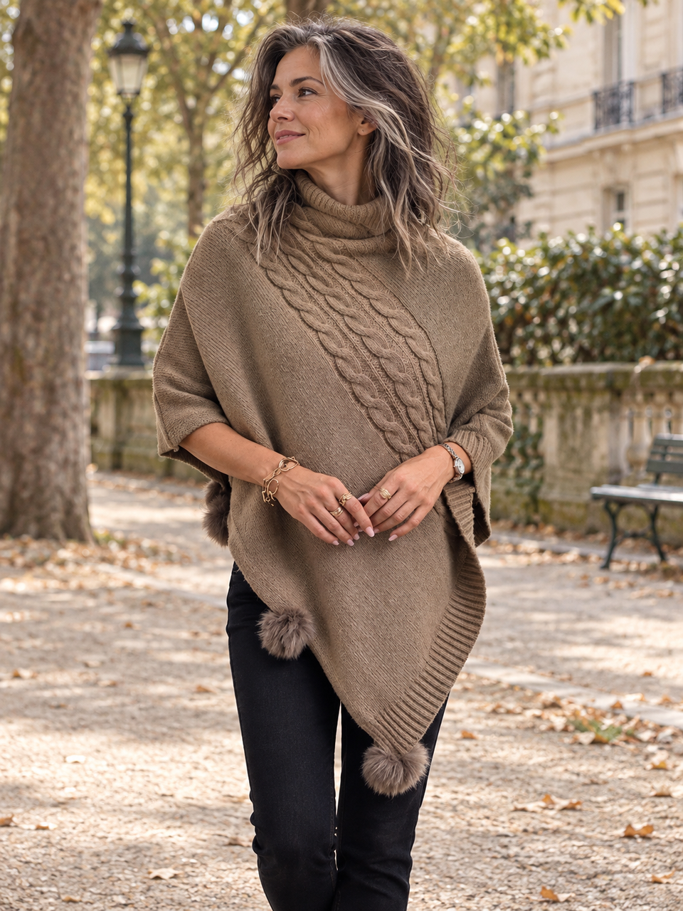 Poncho taupe torsadé à col roulé porté dans un parc.