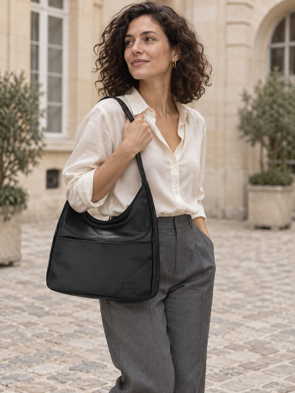 Sac hobo noir porté à l’épaule avec une chemise blanche.